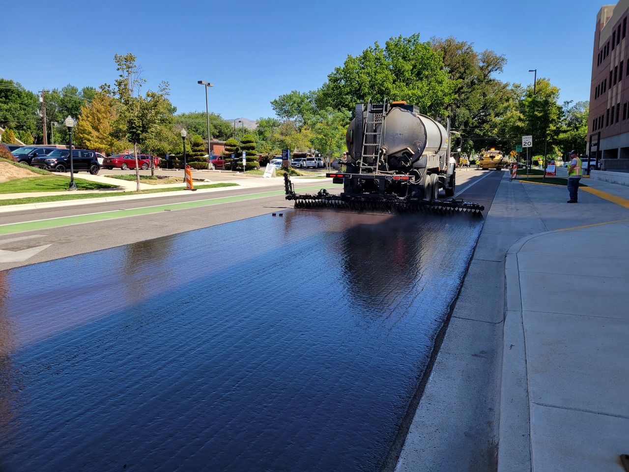 Asphalt truck paving a street in Boise, Idaho, on a sunny day.